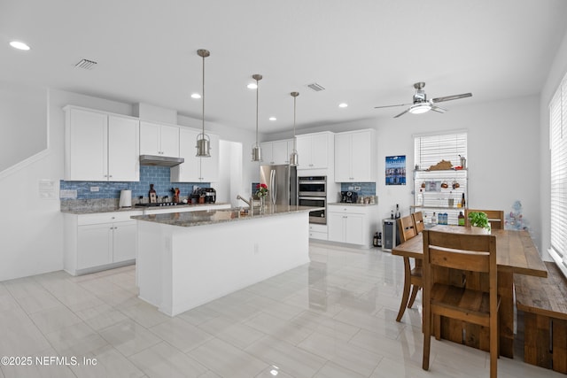 54 Ness Cir, Saint Augustine, FL 32095 - kitchen featuring stainless steel appliances, light stone countertops, visible vents, and an island with sink