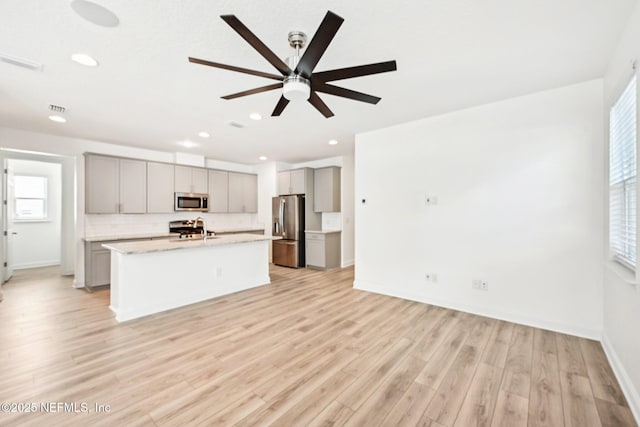 kitchen with appliances with stainless steel finishes, light wood-type flooring, gray cabinetry, and a sink