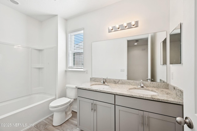 bathroom featuring a sink, toilet, wood finished floors, and double vanity