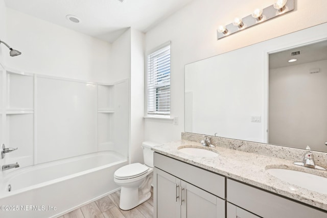 bathroom featuring double vanity, toilet,  shower combination, and a sink