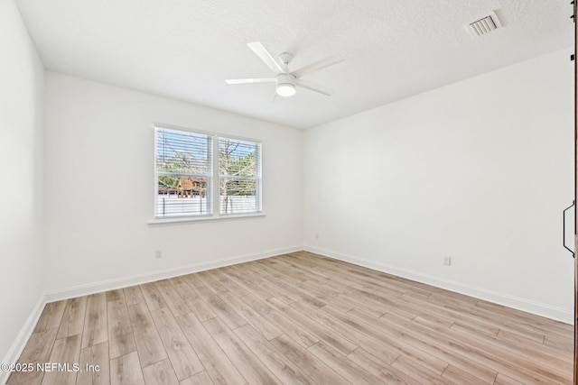 unfurnished room with visible vents, ceiling fan, baseboards, light wood-style floors, and a textured ceiling