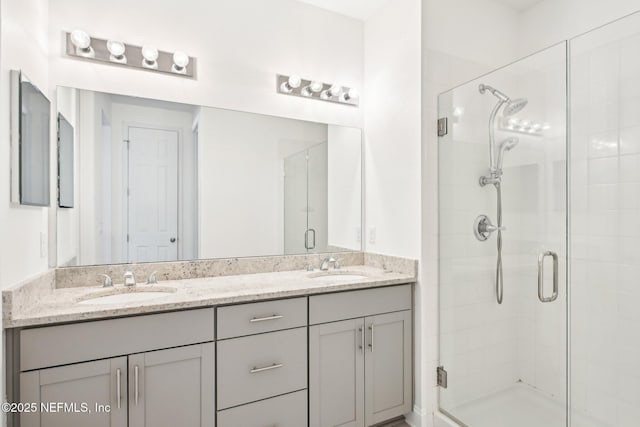 bathroom with double vanity, a stall shower, and a sink