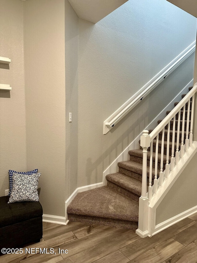 staircase with baseboards and wood finished floors