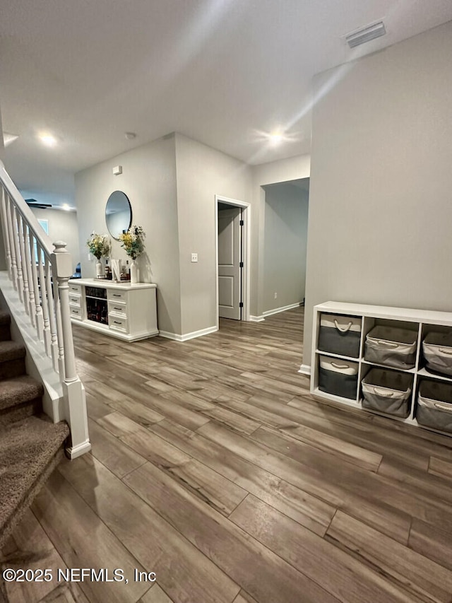 interior space featuring visible vents, baseboards, wood finished floors, and stairs