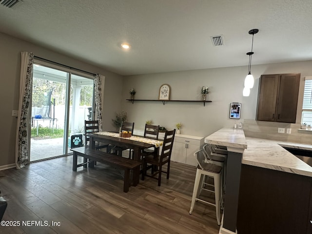 dining area with visible vents, a textured ceiling, and dark wood-type flooring