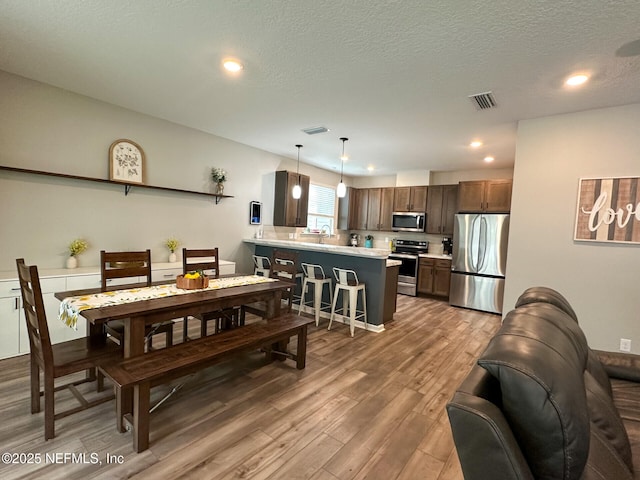 dining area featuring recessed lighting, visible vents, a textured ceiling, and wood finished floors