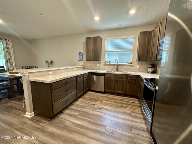 kitchen featuring a sink, stainless steel appliances, a peninsula, and light countertops