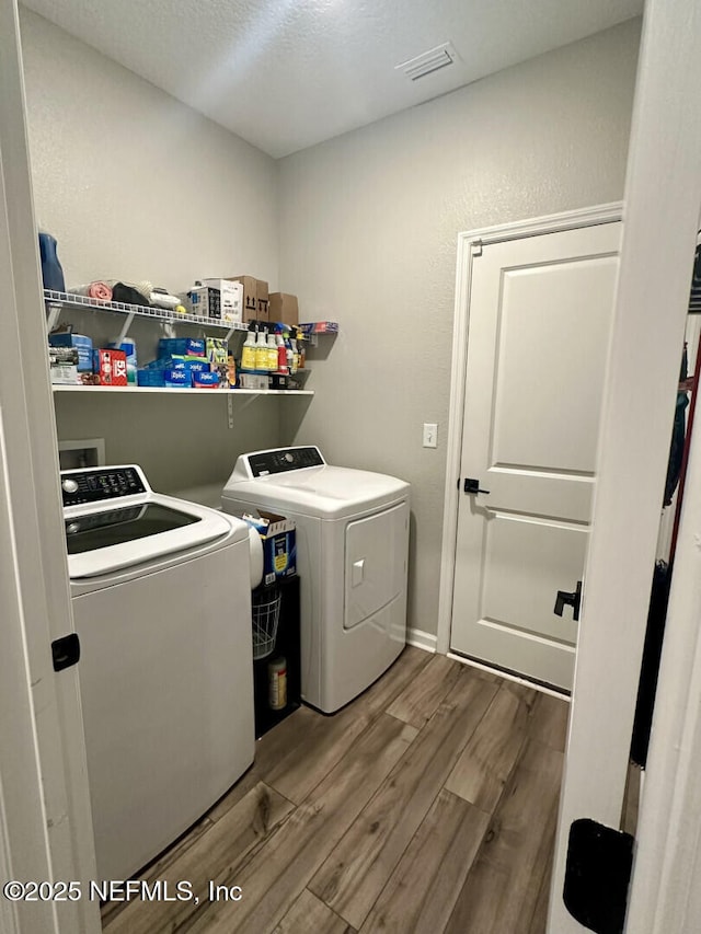 laundry area with visible vents, wood finished floors, laundry area, and washer and clothes dryer