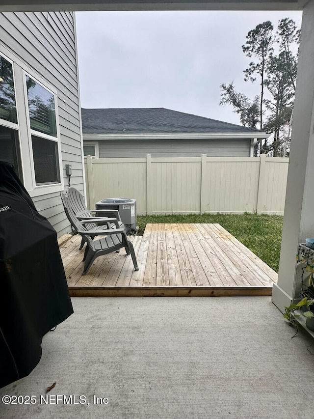 view of patio featuring cooling unit, a wooden deck, and fence