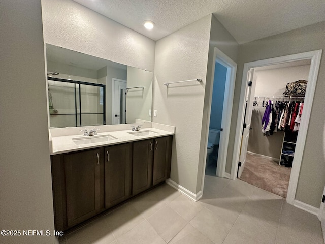 bathroom with a sink, toilet, double vanity, and a shower stall