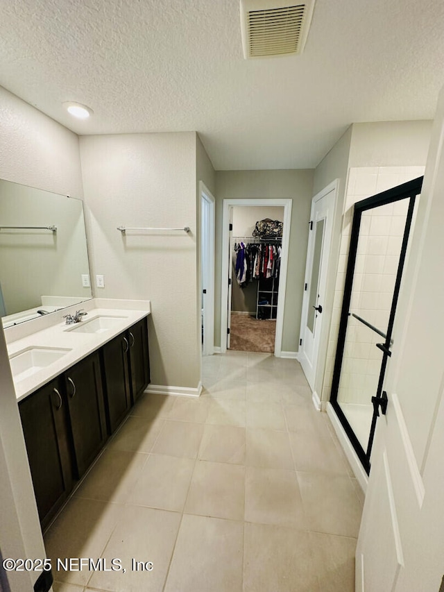 bathroom featuring tile patterned flooring, visible vents, a stall shower, a textured ceiling, and a sink