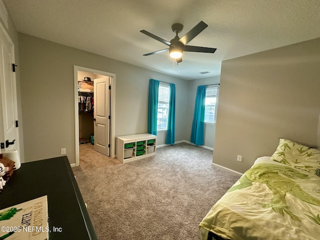 carpeted bedroom with visible vents, baseboards, ceiling fan, a spacious closet, and a textured ceiling