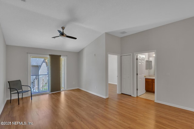 interior space with baseboards, light wood-style flooring, vaulted ceiling, and access to outside