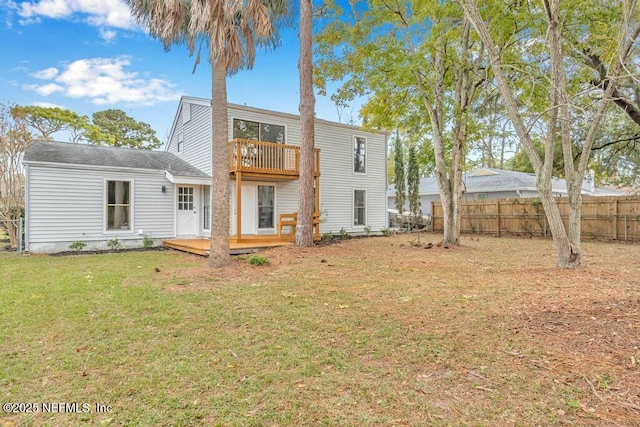 back of house with a deck, a lawn, a balcony, and fence