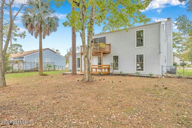 rear view of property with a lawn, a deck, fence, a balcony, and a chimney