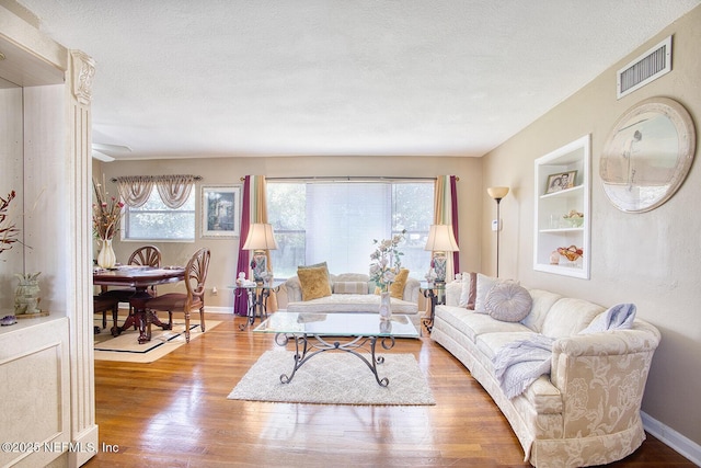 living room featuring visible vents, a healthy amount of sunlight, a textured ceiling, and wood finished floors