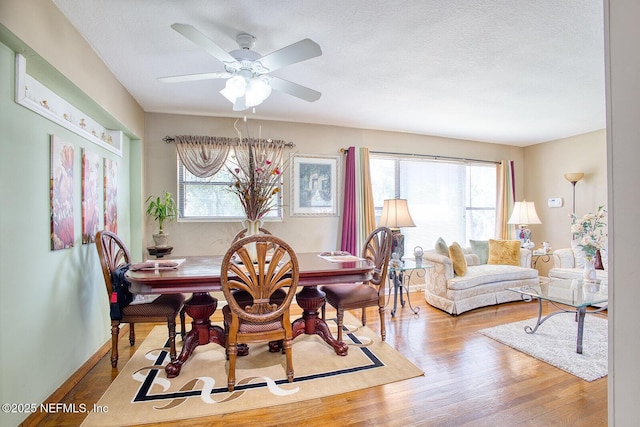 dining area featuring a textured ceiling, a ceiling fan, baseboards, and wood finished floors