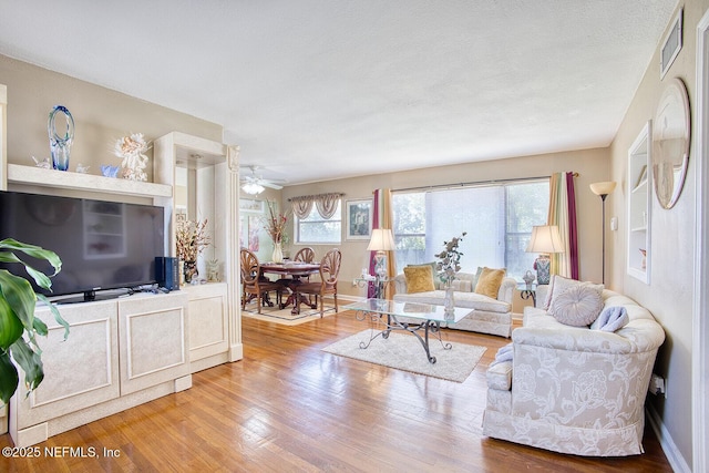 living area featuring plenty of natural light, visible vents, and wood finished floors