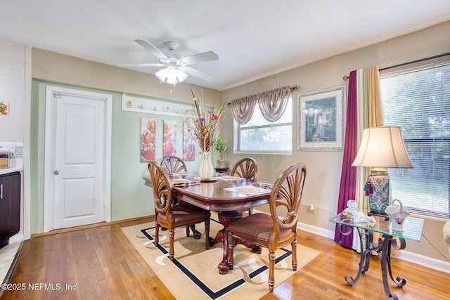 dining space with baseboards, light wood-style floors, and ceiling fan