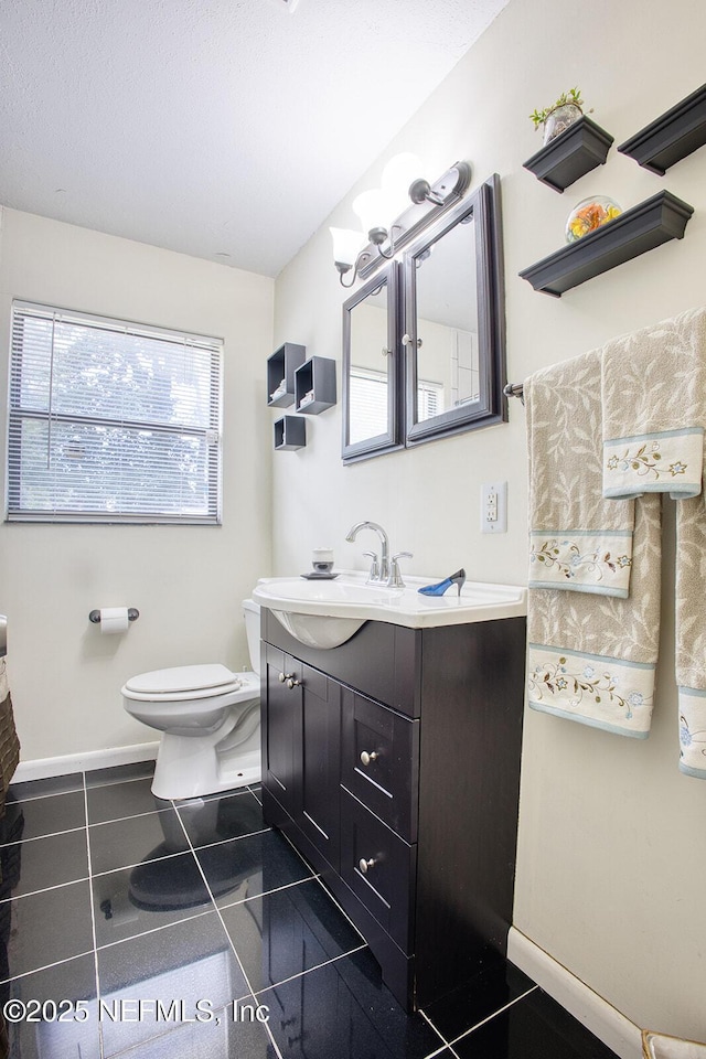 bathroom featuring tile patterned flooring, toilet, vanity, and baseboards