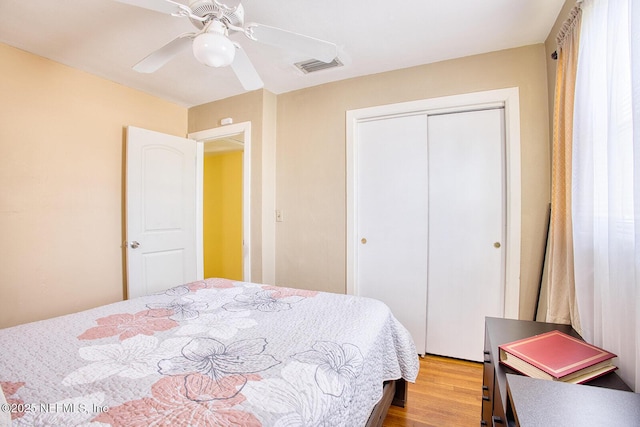 bedroom featuring a closet, visible vents, a ceiling fan, and wood finished floors