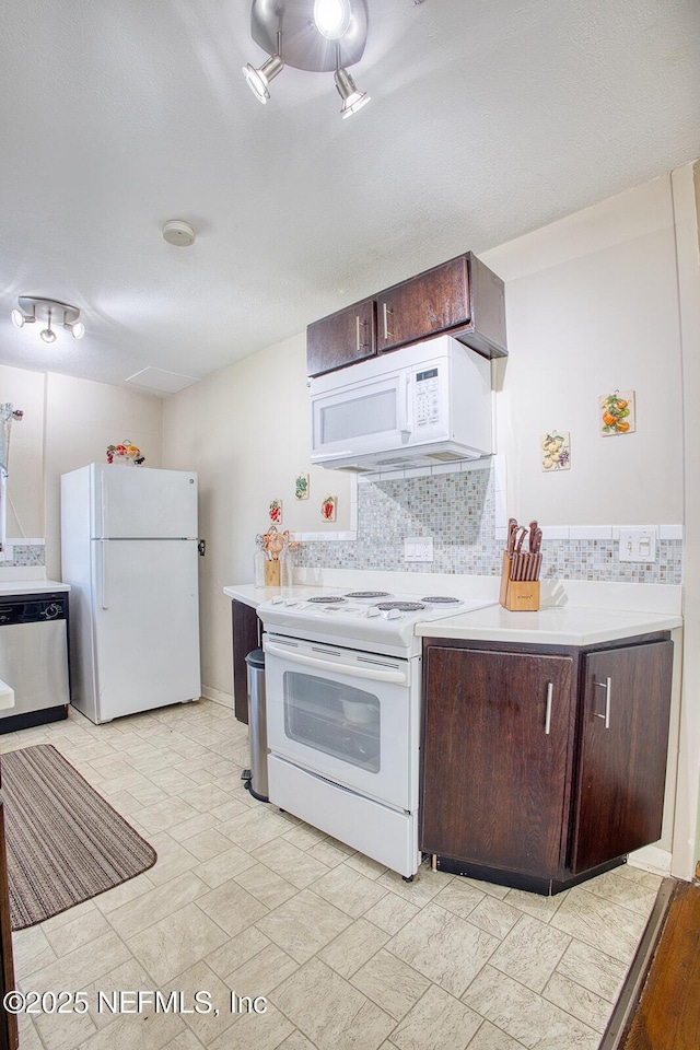 kitchen featuring decorative backsplash, white appliances, dark brown cabinetry, and light countertops