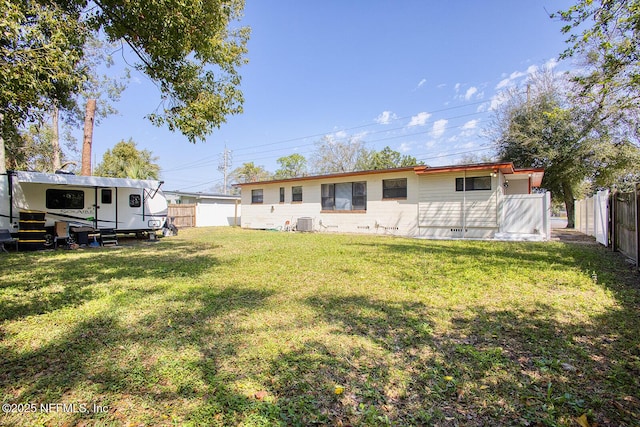 rear view of property with central AC, a lawn, and a fenced backyard