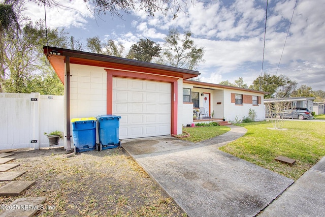 single story home with concrete block siding, a front yard, fence, concrete driveway, and a garage