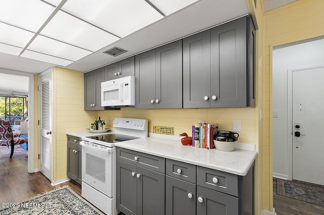 kitchen with visible vents, white appliances, dark wood-style floors, and gray cabinets