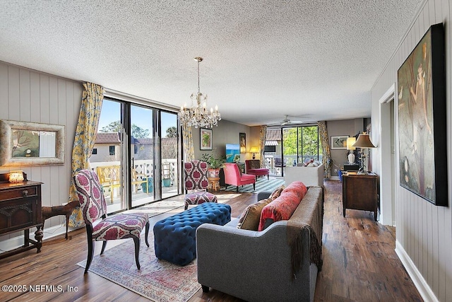 living room featuring baseboards, a textured ceiling, an inviting chandelier, and wood finished floors