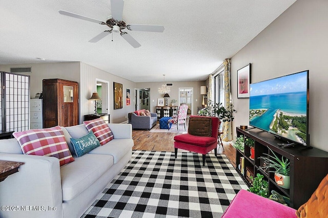 living room with visible vents, a textured ceiling, ceiling fan, and wood finished floors