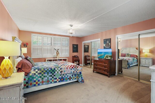 bedroom featuring carpet flooring, multiple closets, and a textured ceiling