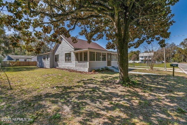 view of side of property featuring fence, a lawn, and a sunroom