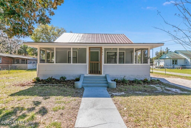 view of front of house featuring fence, a front lawn, and a sunroom