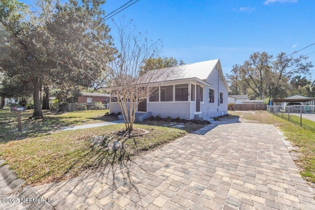 view of front of property featuring decorative driveway, metal roof, and fence