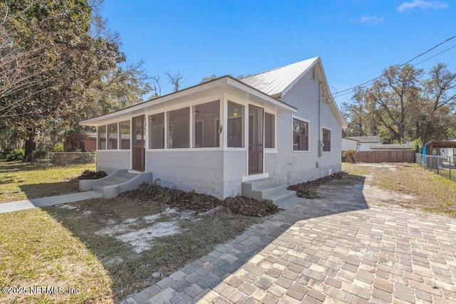 bungalow-style house featuring entry steps, metal roof, fence, and a sunroom