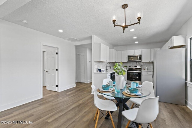 dining room featuring recessed lighting, a textured ceiling, baseboards, and wood finished floors