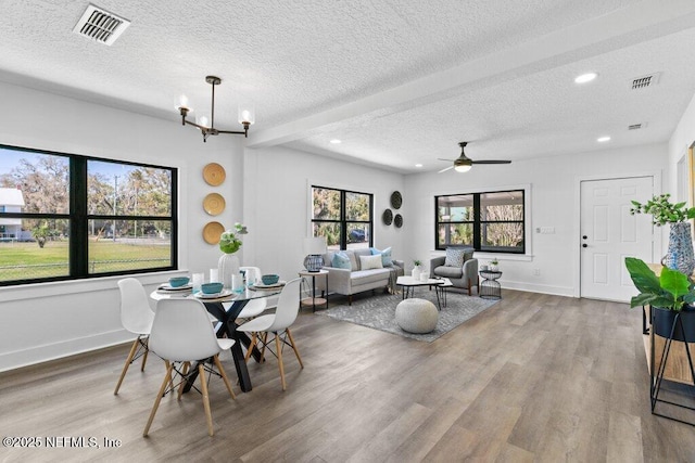 dining area featuring visible vents, baseboards, a textured ceiling, and wood finished floors