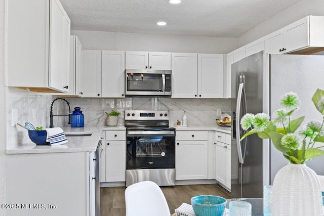 kitchen with a sink, stainless steel appliances, backsplash, and white cabinets