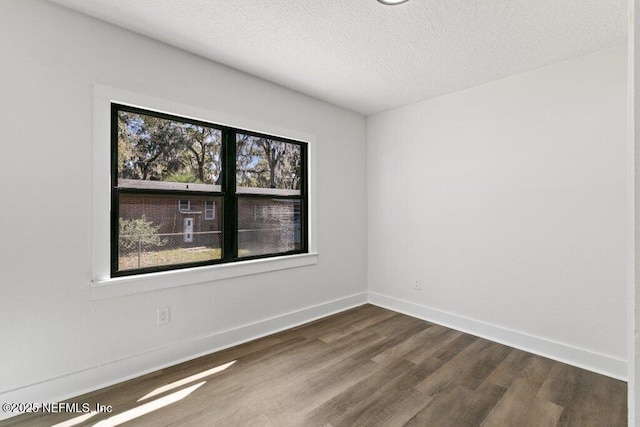 spare room with dark wood finished floors, a textured ceiling, and baseboards