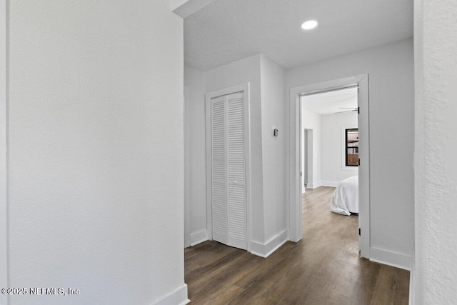 corridor featuring dark wood finished floors and baseboards