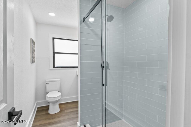 bathroom featuring baseboards, toilet, wood finished floors, and a shower stall