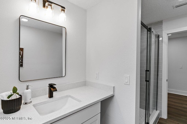 bathroom featuring visible vents, a stall shower, wood finished floors, a textured ceiling, and vanity