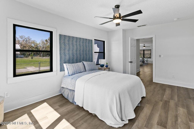 bedroom with baseboards, wood finished floors, visible vents, and a textured ceiling