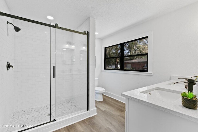 full bathroom featuring wood finished floors, a stall shower, and a sink