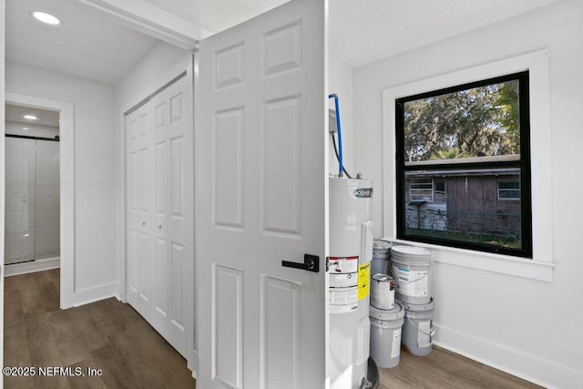 interior space featuring dark wood-style floors, water heater, and baseboards