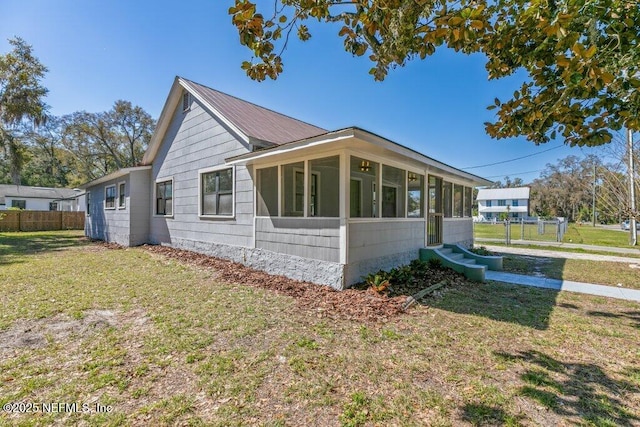 view of home's exterior with fence, a yard, and a sunroom