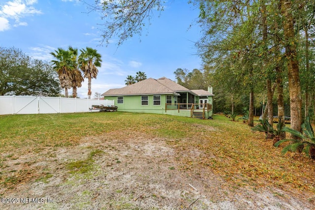 back of house featuring fence, a yard, and a sunroom