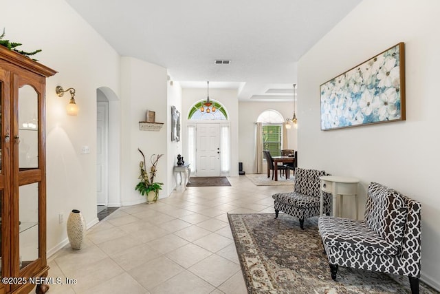 foyer entrance featuring light tile patterned floors, visible vents, arched walkways, and baseboards