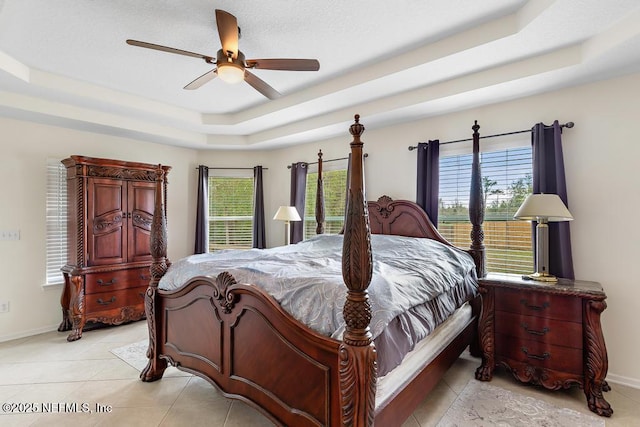 bedroom with a tray ceiling, multiple windows, baseboards, and ceiling fan